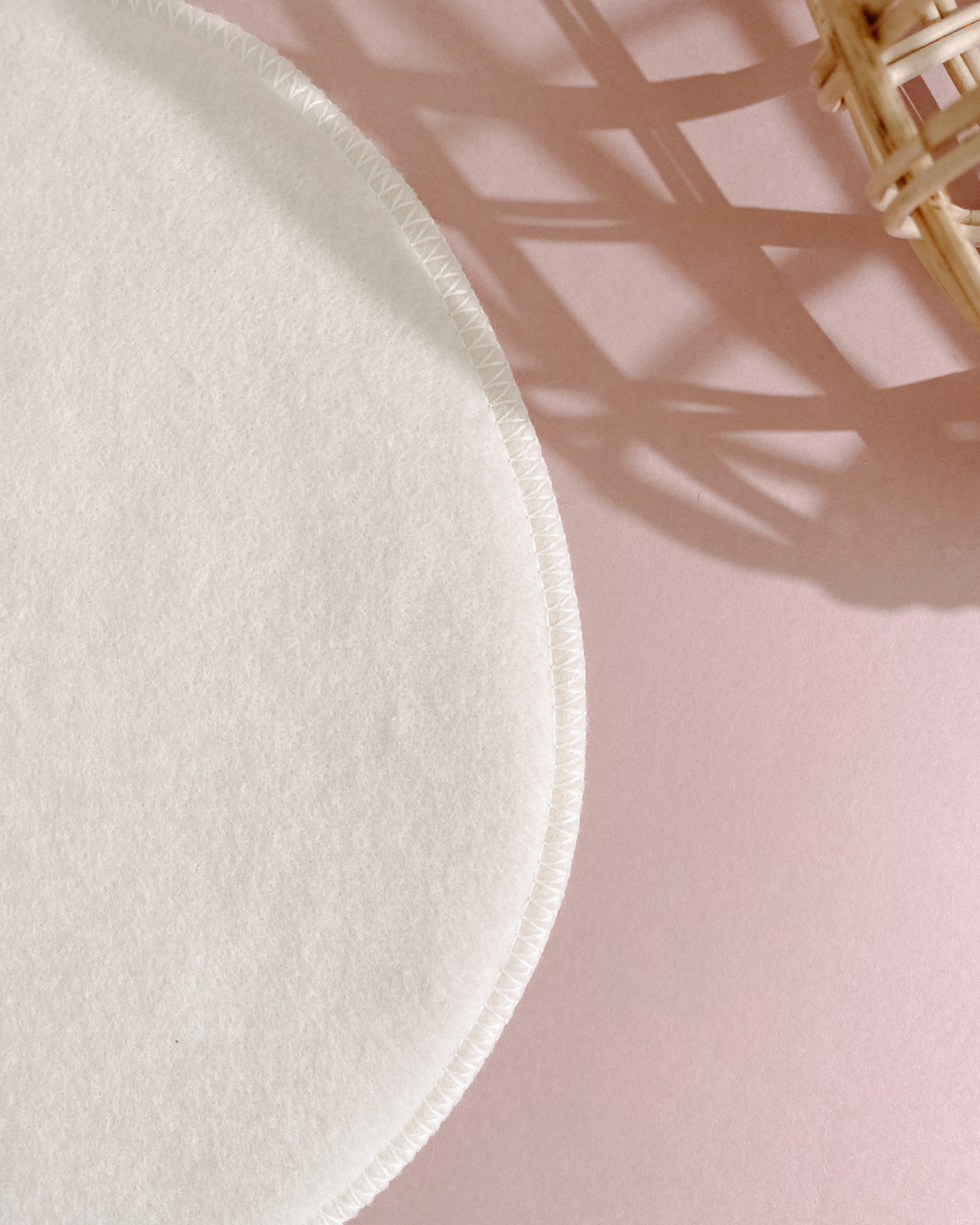 White round cloth on a pink surface with a wicker basket in the corner