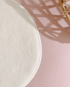 White round cloth on a pink surface with a wicker basket in the corner