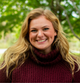 Woman with blonde hair wearing a maroon sweater in a natural setting