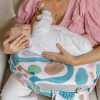 Woman holding a baby on a colorful baby carrier