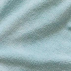 Close-up of soft, textured, light blue fabric with gentle folds and a cozy, relaxed feel, suggesting comfort and warmth.