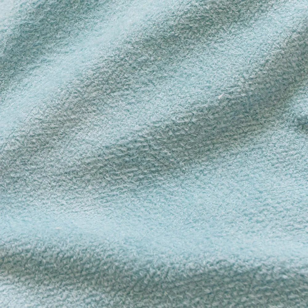 Close-up of soft, textured, light blue fabric with gentle folds and a cozy, relaxed feel, suggesting comfort and warmth.