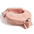 A pink, plush breastfeeding pillow with an ergonomic shape. It features a small pouch and an adjustable strap, conveying comfort and utility.