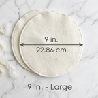Two round white pads with measurements on a marble background