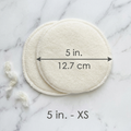 Two circular white pads on a marble surface with measurements indicated.