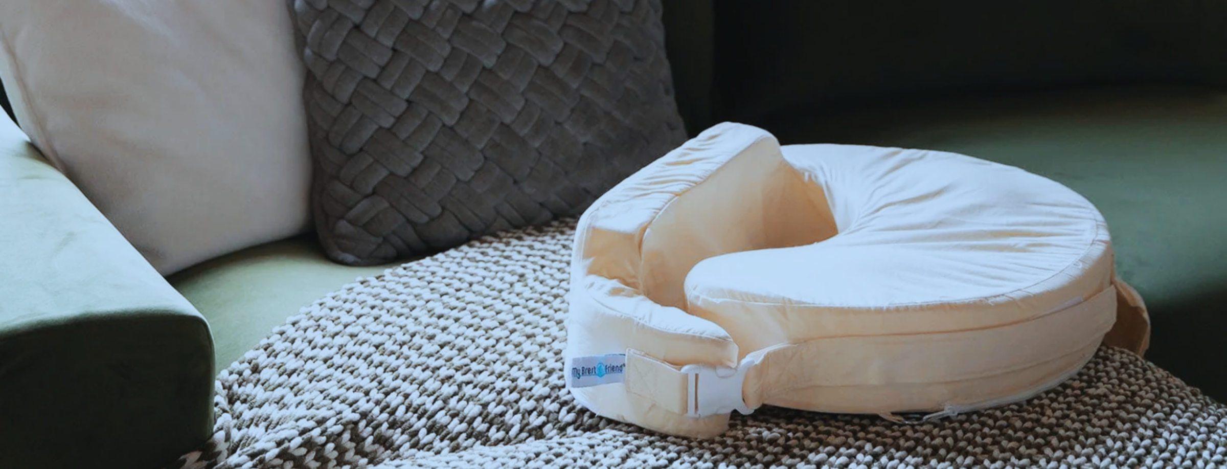Beige Nursing pillow on a textured surface with a couch in the background