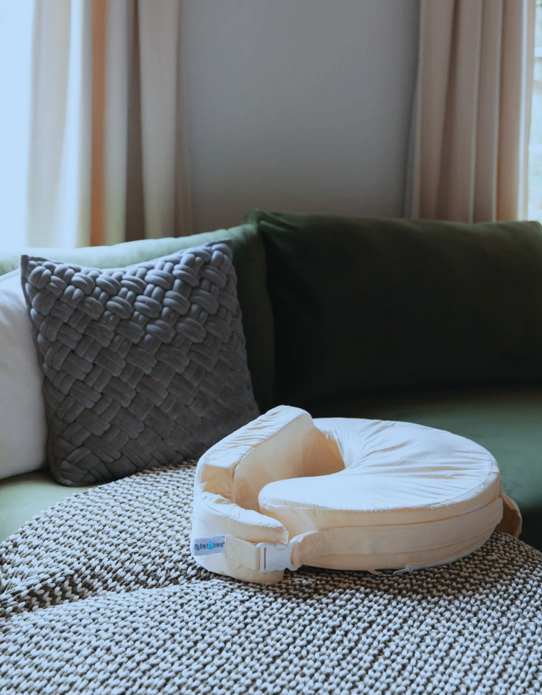 Baby Nursing pillow on a textured surface with a couch and curtains in the background