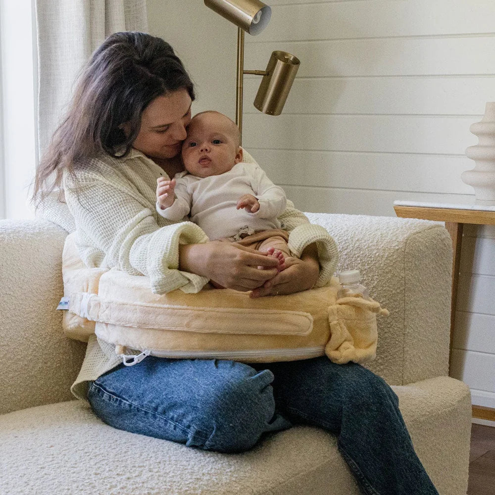 Woman holding a baby in a baby carrier on a couch